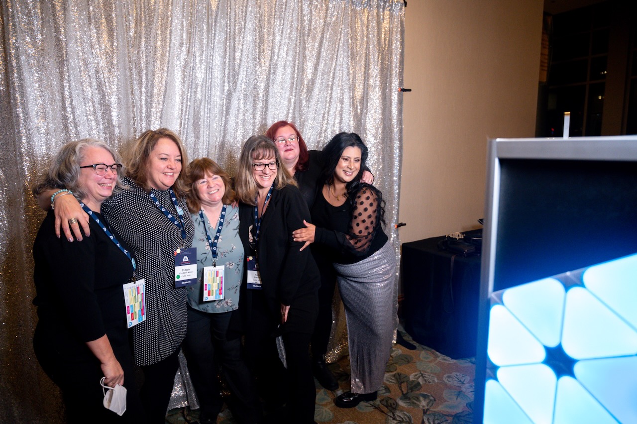 Six party-goers in front of a shiny backdrop